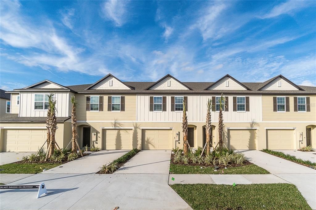 A row of modern townhouses with beige siding, attached garages, and small front landscaping — 32123 POND APPLE BEND, SAN ANTONIO, FL