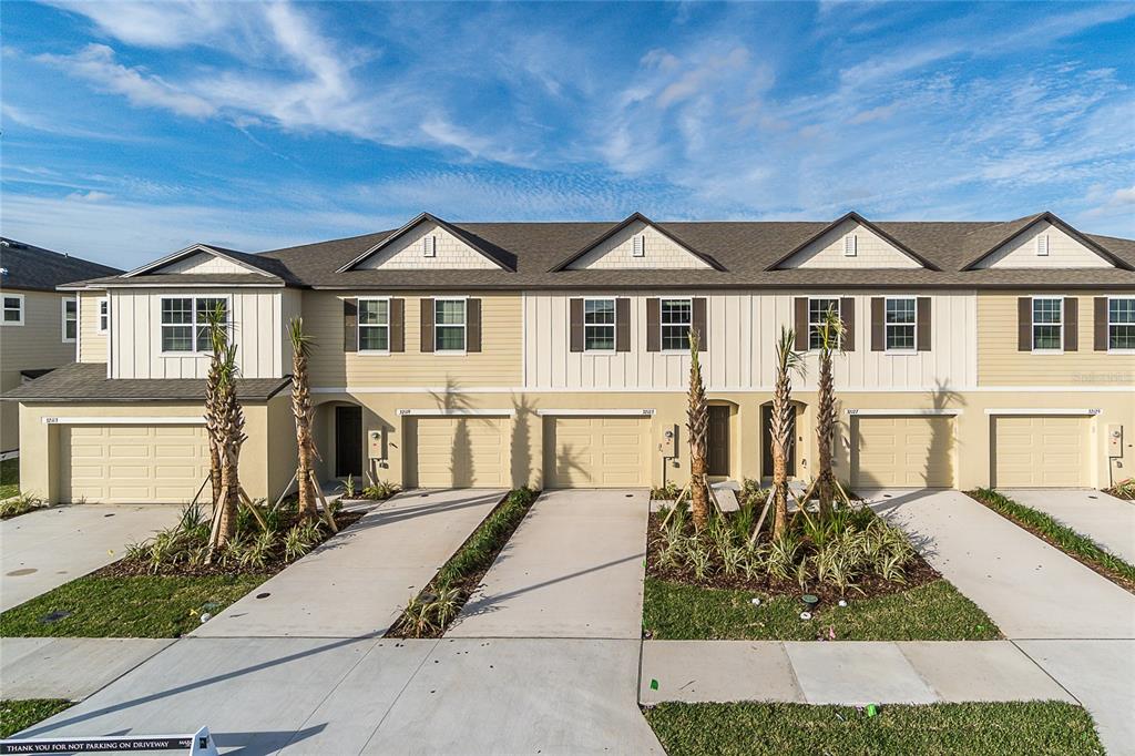 A row of multi-story townhomes with beige siding, attached garages, and small front landscaping — 32123 POND APPLE BEND, SAN ANTONIO, FL