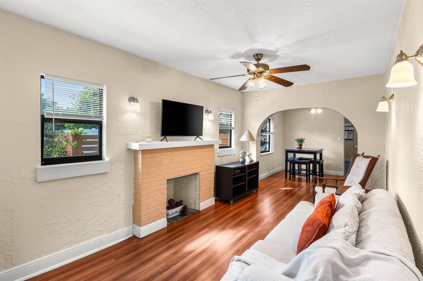 A living room features a brick fireplace, hardwood floors, and an arched entryway to a dining area — 921 S M Street, FL 33460, FL