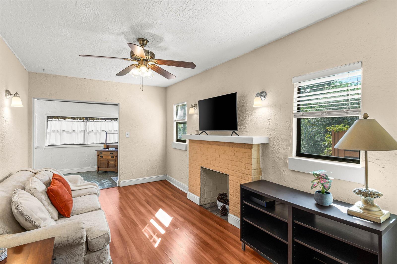 A living room features a brick fireplace, a ceiling fan, and hardwood-style flooring — 921 S M Street, FL 33460, FL
