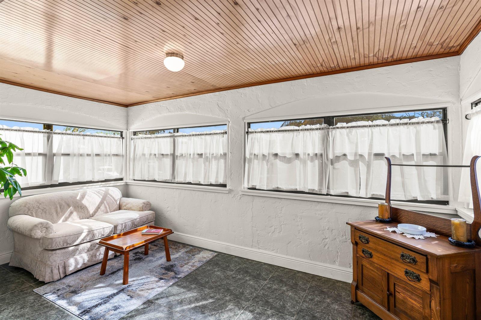 A sunroom with a wood-paneled ceiling, white textured walls, tile flooring, and multiple windows — 921 S M Street, FL 33460, FL