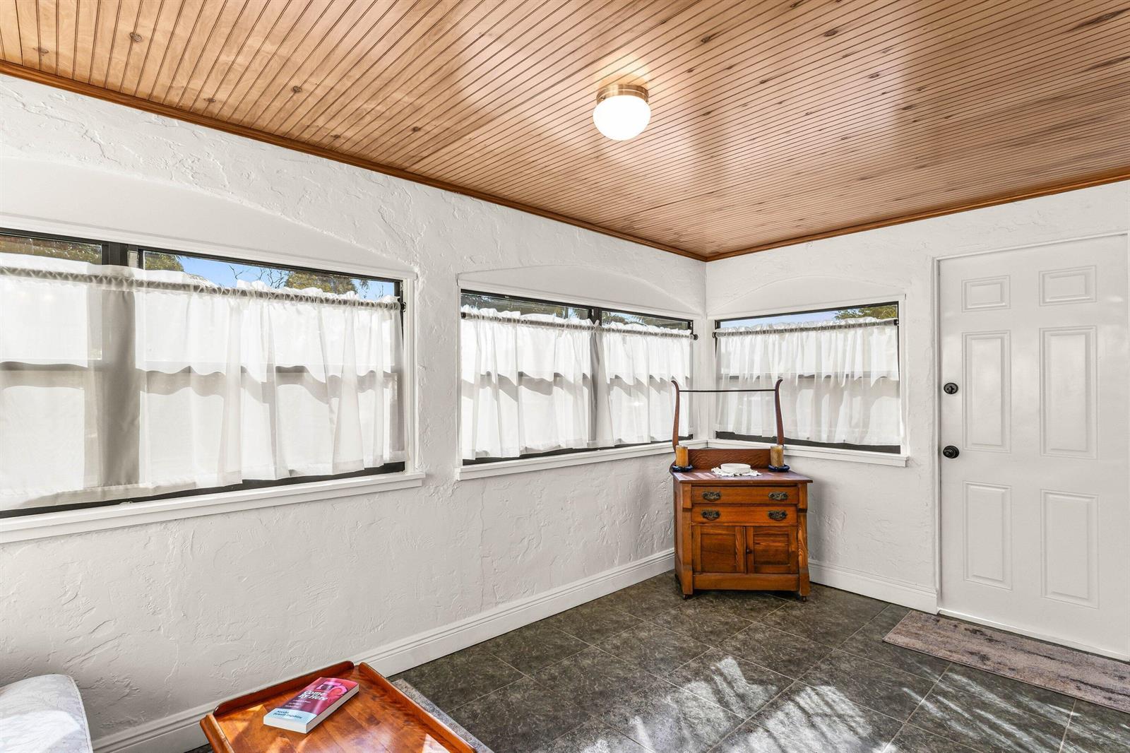 A sunroom features a wood-paneled ceiling, white textured walls, tile flooring, and three windows — 921 S M Street, FL 33460, FL