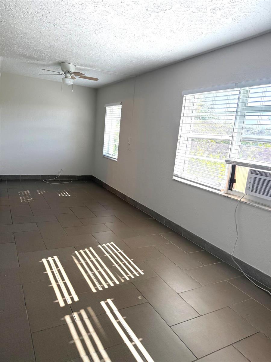 An empty room with brown tile flooring, a ceiling fan, and two windows with blinds — 605 N Federal Highway # 14, FL 33460, FL
