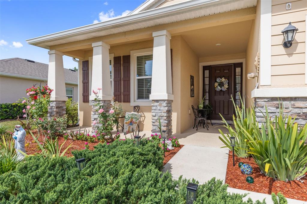 The exterior of a house features a covered porch with stone columns and a front garden — 12421 EASTPOINTE DRIVE, DADE CITY, FL