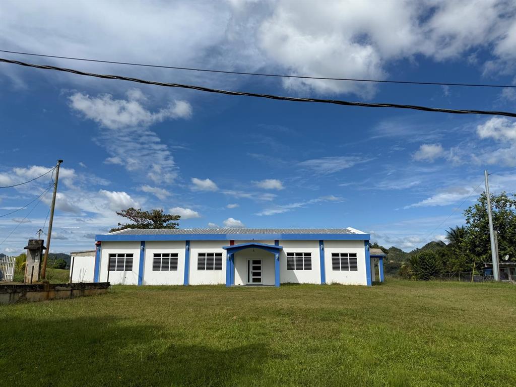A single-story white building with a blue roof and trim sits on a grassy lot — 111 CARR 111 R 602 KM 1.2 INT. BO ANGELES, ANGELES, PR