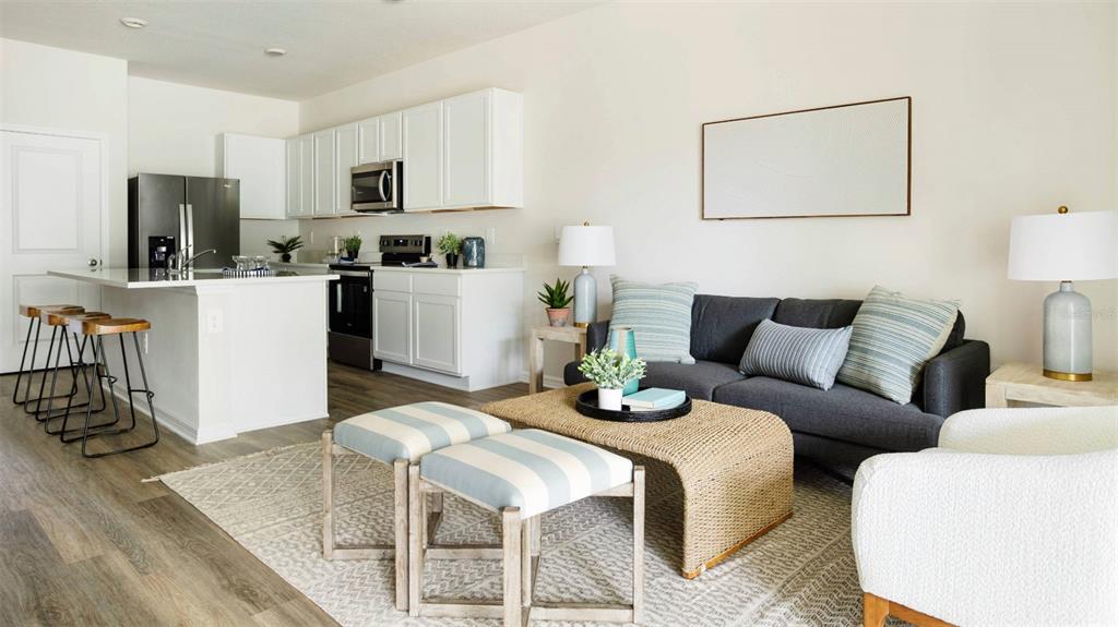 An open-concept living room and kitchen featuring white cabinets, stainless appliances, and a gray sofa — 4080 GOLD DUST LANE, SARASOTA, FL