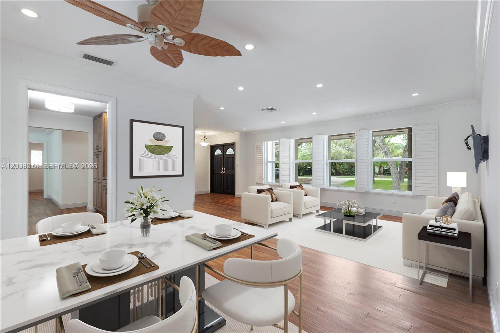 A dining area and living room feature white furniture, wood flooring, and large windows — 7715 SW 122nd St, Pinecrest FL 33156, PINECREST, FL