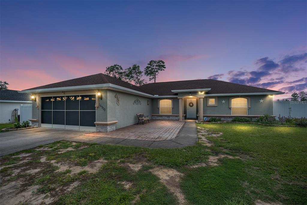A single-story house with a two-car garage and a paved front patio at dusk — 16900 SW 42ND AVENUE ROAD, OCALA, FL