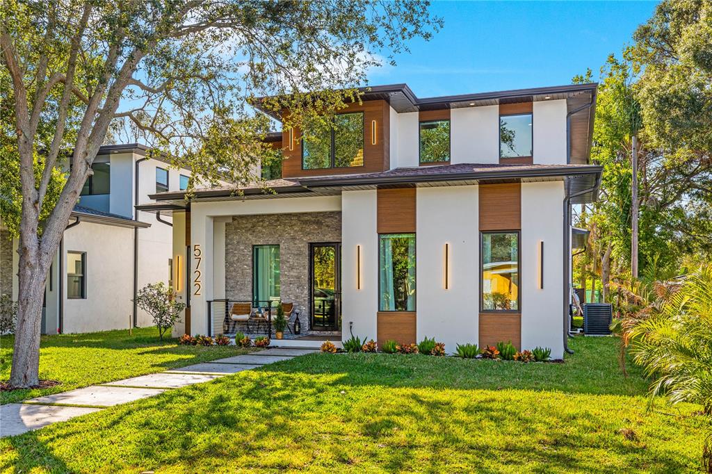 A modern kitchen with light wood cabinets and a white island opens into a living area — 6325 11TH AVENUE S, GULFPORT, FL