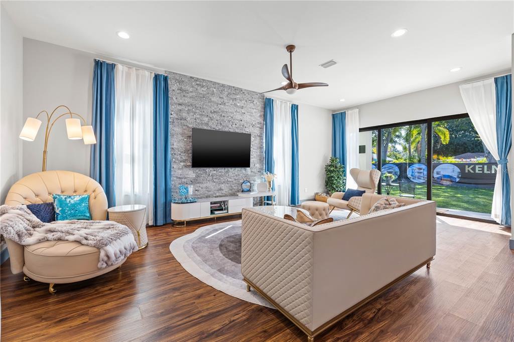 A bright living room features light wood floors, a modern ceiling fan, and neutral furniture — 6325 11TH AVENUE S, GULFPORT, FL