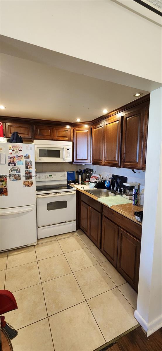 A kitchen features dark wood cabinets, white appliances, granite countertops, and light-colored tile flooring — 191 E Preston  E # 191, Boca Raton FL 33434, BOCA RATON, FL