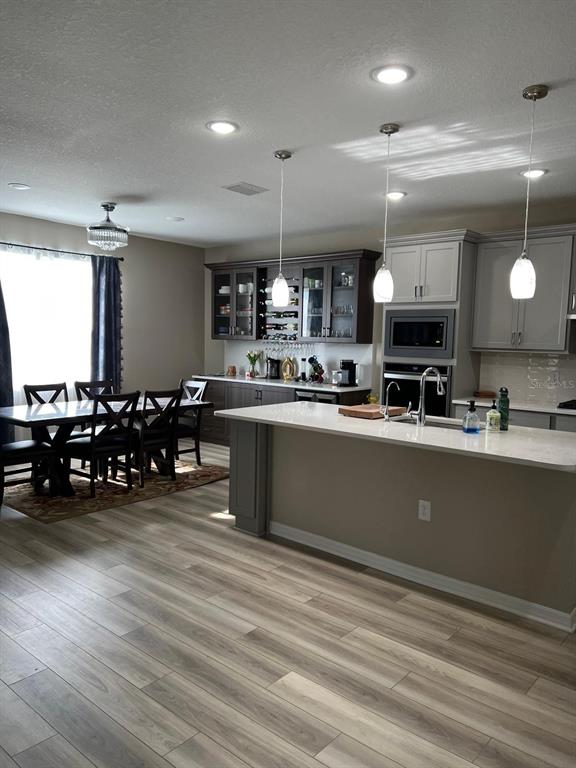 A kitchen with a large island, gray cabinetry, and an adjacent dining area with wood flooring — 3900 ALMOND BROOK BOULEVARD, LAND O LAKES, FL