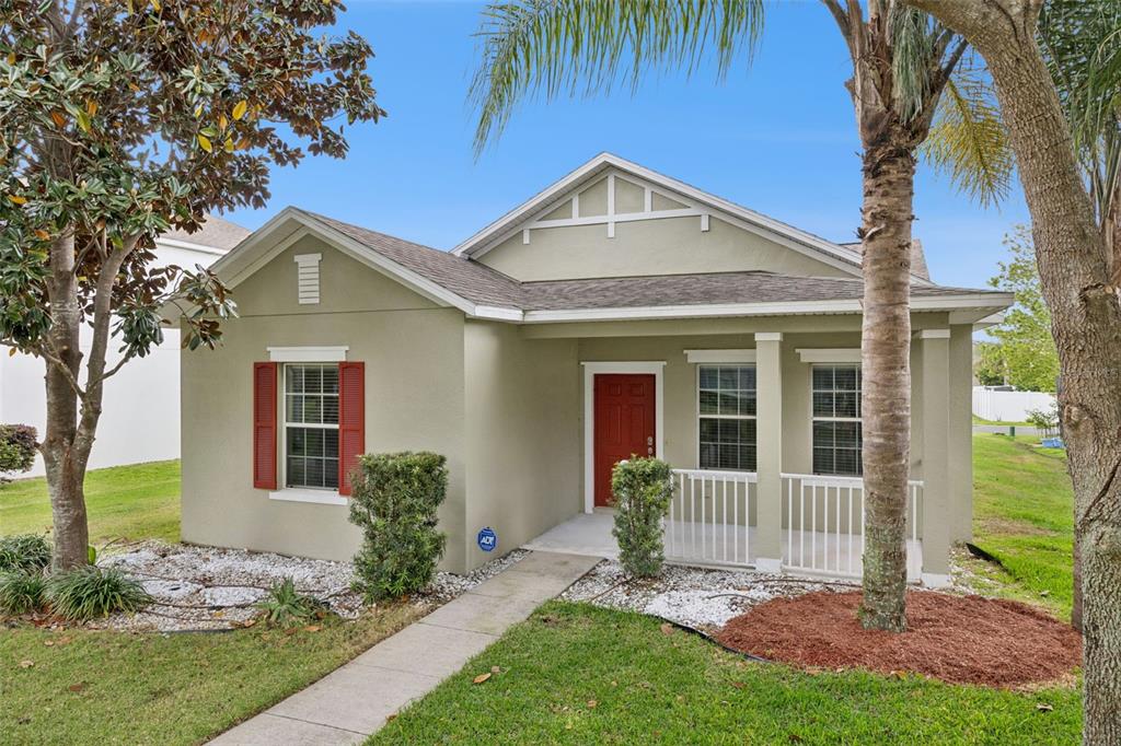A single-story house with light green stucco, a red front door, and a front porch — 1916 RUCKMAN PLACE, APOPKA, FL