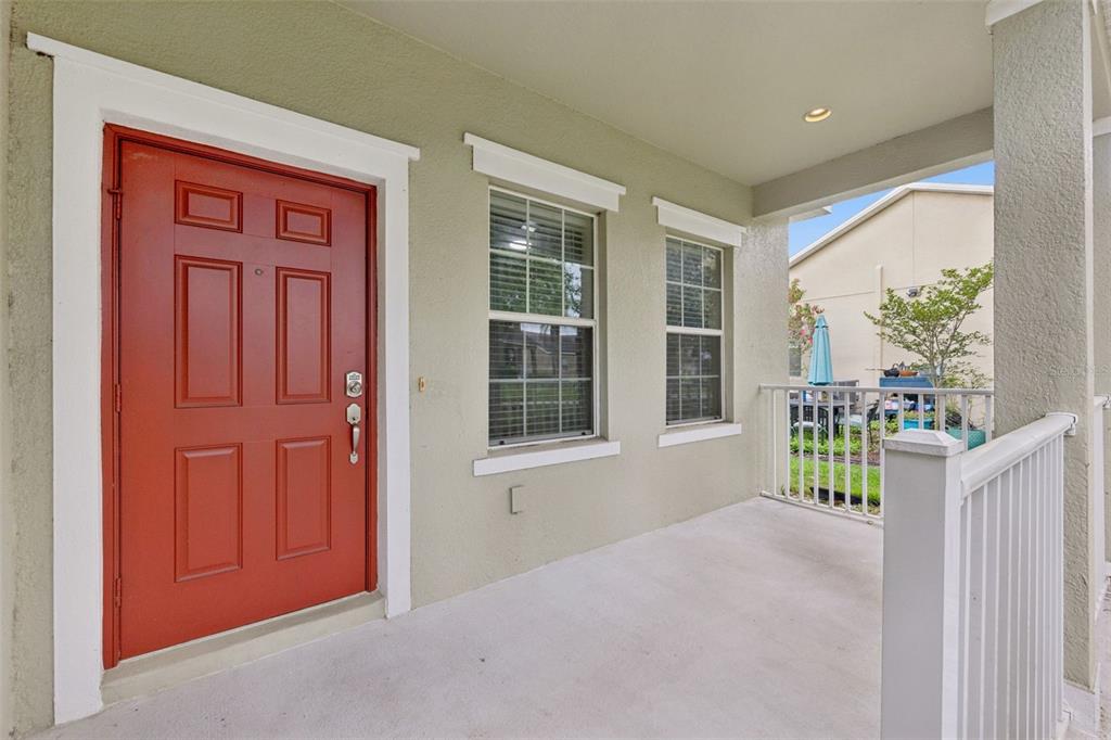A covered porch features a red front door, two windows, and a white railing — 1916 RUCKMAN PLACE, APOPKA, FL