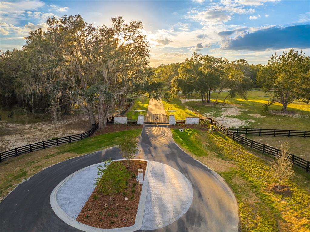 An aerial view shows a paved circular driveway leading to a gated entrance on a property — 17197 SW 11 COURT, NEWBERRY, FL