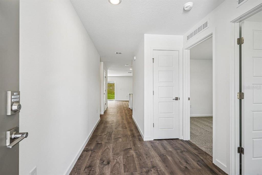 A bright hallway with wood-look flooring leads toward an open living area — 234 BULL FROG LANE, UMATILLA, FL