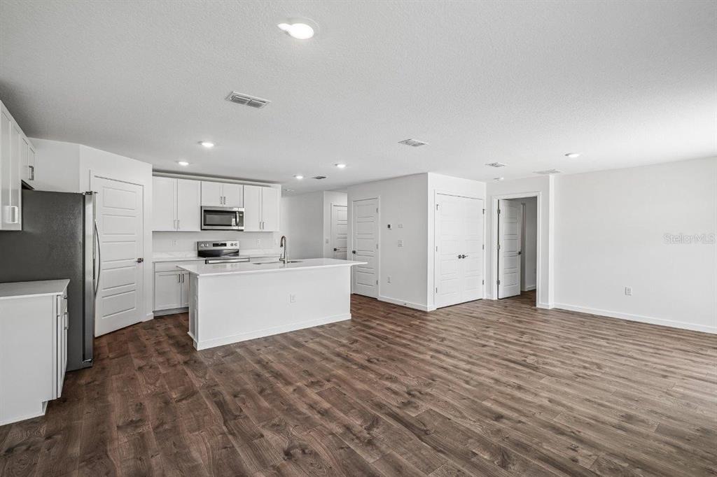 A modern kitchen with white cabinets and a center island opens into a living area — 234 BULL FROG LANE, UMATILLA, FL