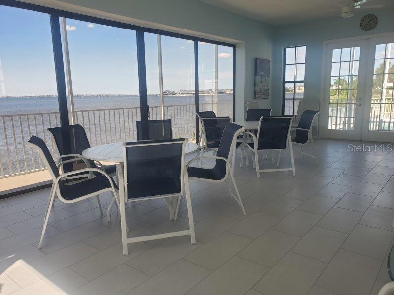 A sunroom with tile flooring, patio furniture, and large windows overlooking a body of water — 1600 W MARION AVENUE UNIT 232, PUNTA GORDA, FL