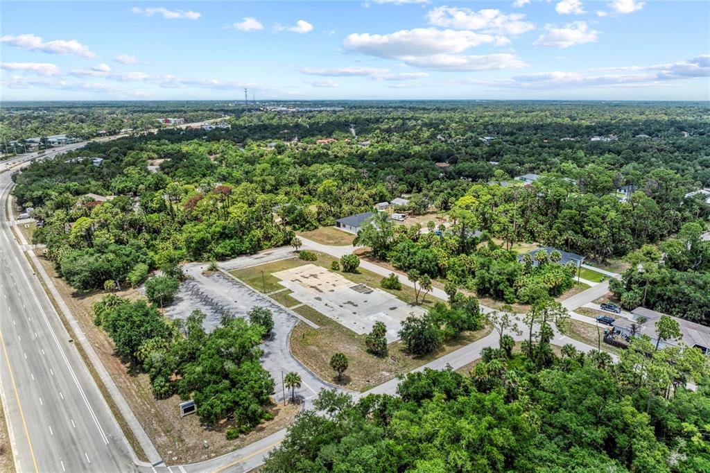 An aerial view shows a paved parking lot and a concrete foundation surrounded by trees — 640 TAMIAMI TRAIL, PORT CHARLOTTE, FL
