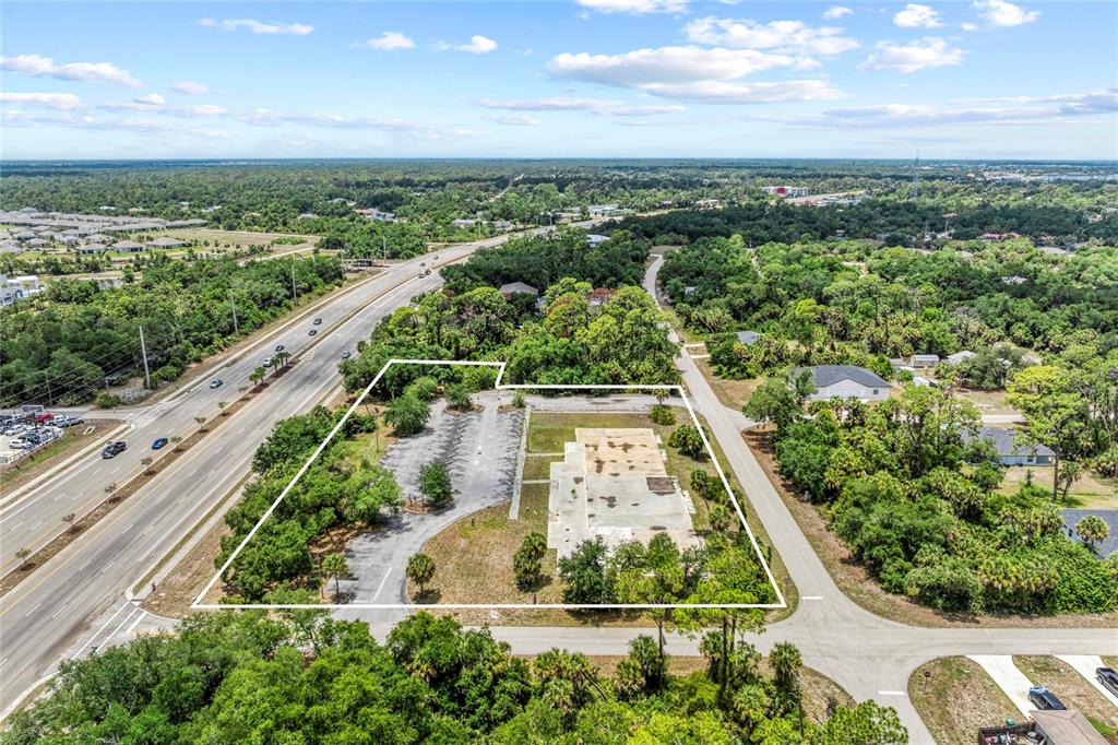 An aerial view shows a vacant lot with a concrete slab and parking area — 640 TAMIAMI TRAIL, PORT CHARLOTTE, FL