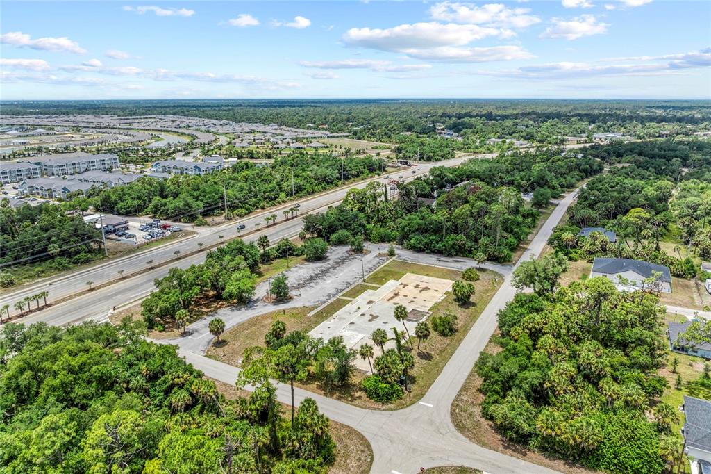 An aerial view shows a vacant concrete lot with surrounding trees and a nearby road — 640 TAMIAMI TRAIL, PORT CHARLOTTE, FL
