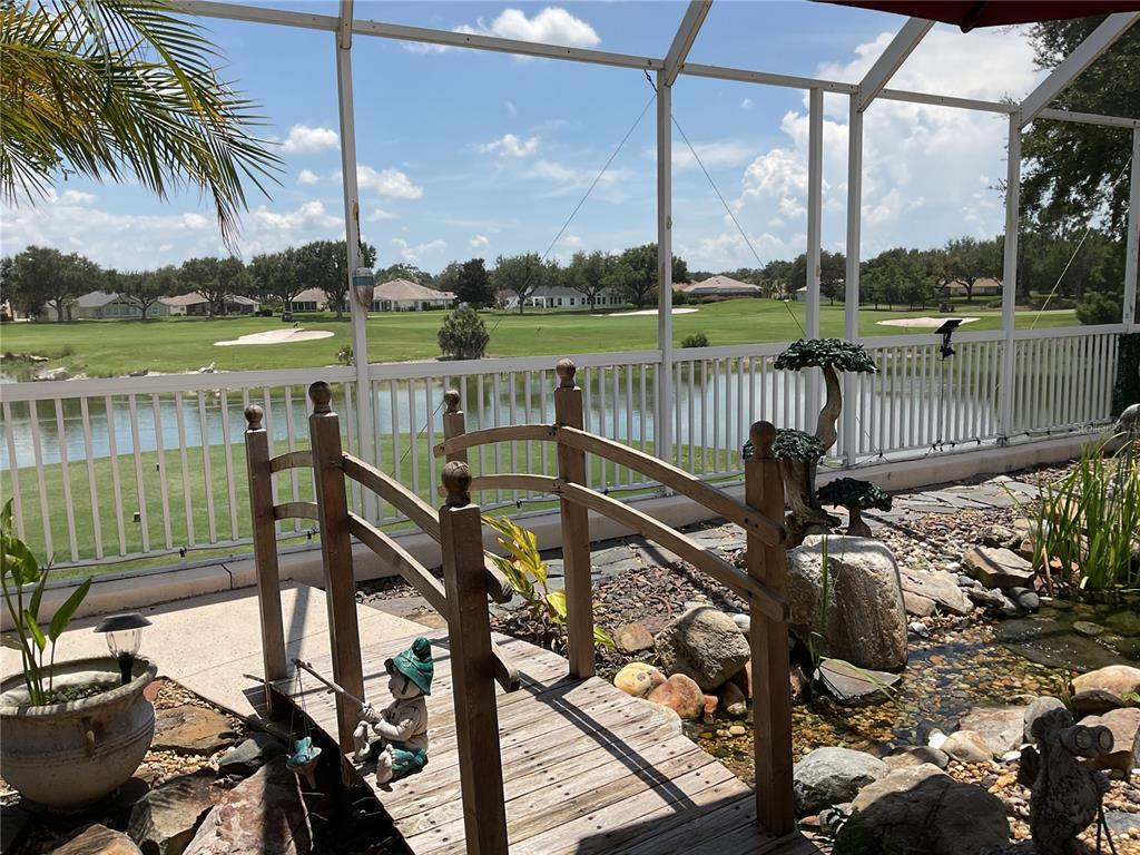 A kitchen island with a black sink overlooks an open-concept living area and outdoor patio — 17116 SE 79TH MCLAWREN TERRACE, THE VILLAGES, FL