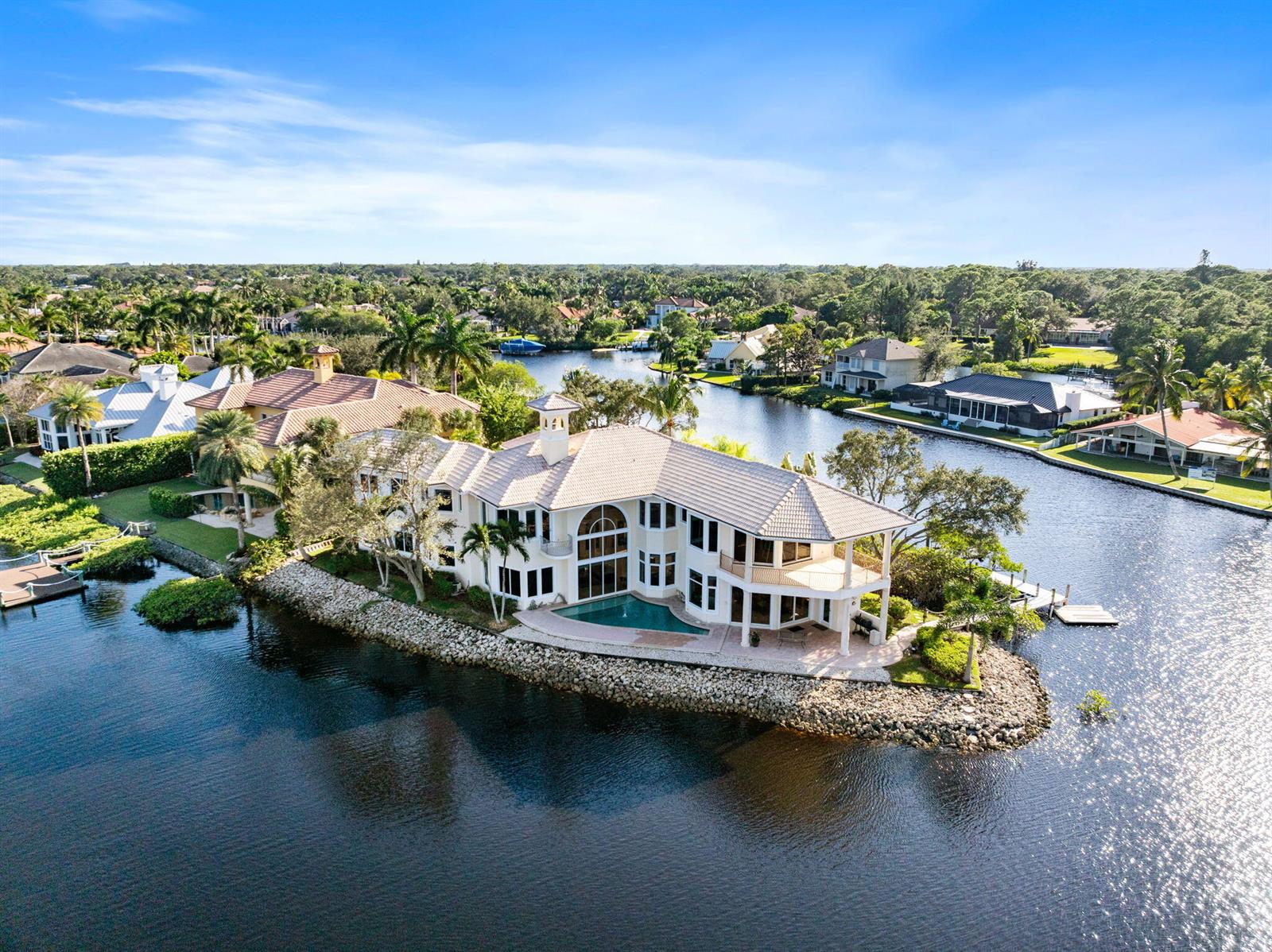 An aerial view of a large waterfront house with a pool on a point lot — 18499 SE Palm Island Lane, Jupiter FL 33458, JUPITER, FL