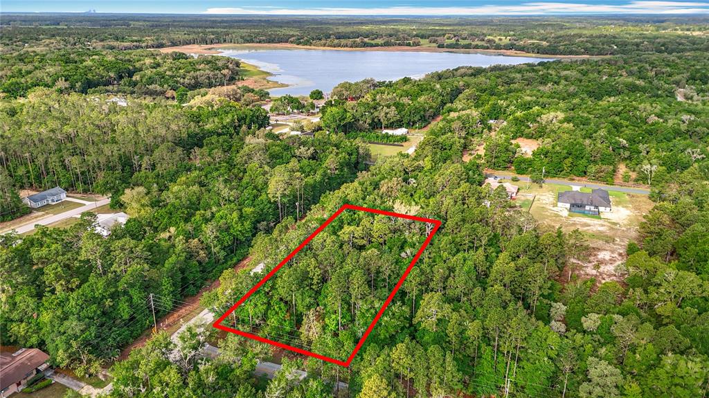 An aerial view shows a rectangular plot of land outlined in red amidst dense forest — 0 SW BREEZY POINT DRIVE, DUNNELLON, FL
