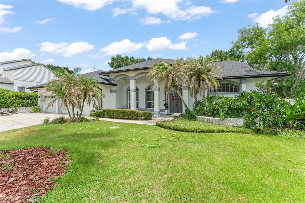 A single-story house with a gray roof, arched windows, and palm trees in the front yard — 551 WHEATSTONE PLACE, ORLANDO, FL