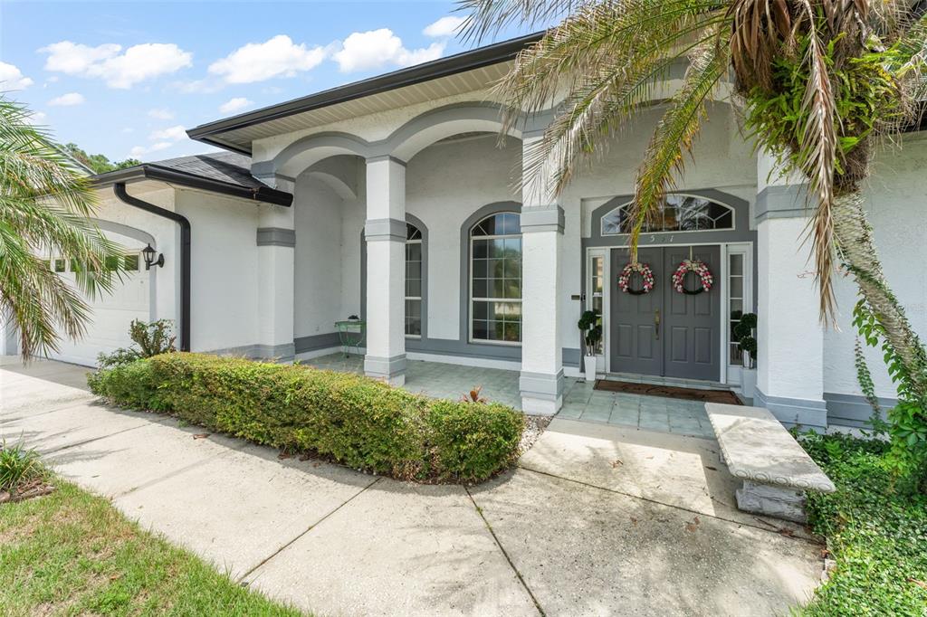 A white stucco house with gray trim, arched columns, and a double front door entrance — 551 WHEATSTONE PLACE, ORLANDO, FL