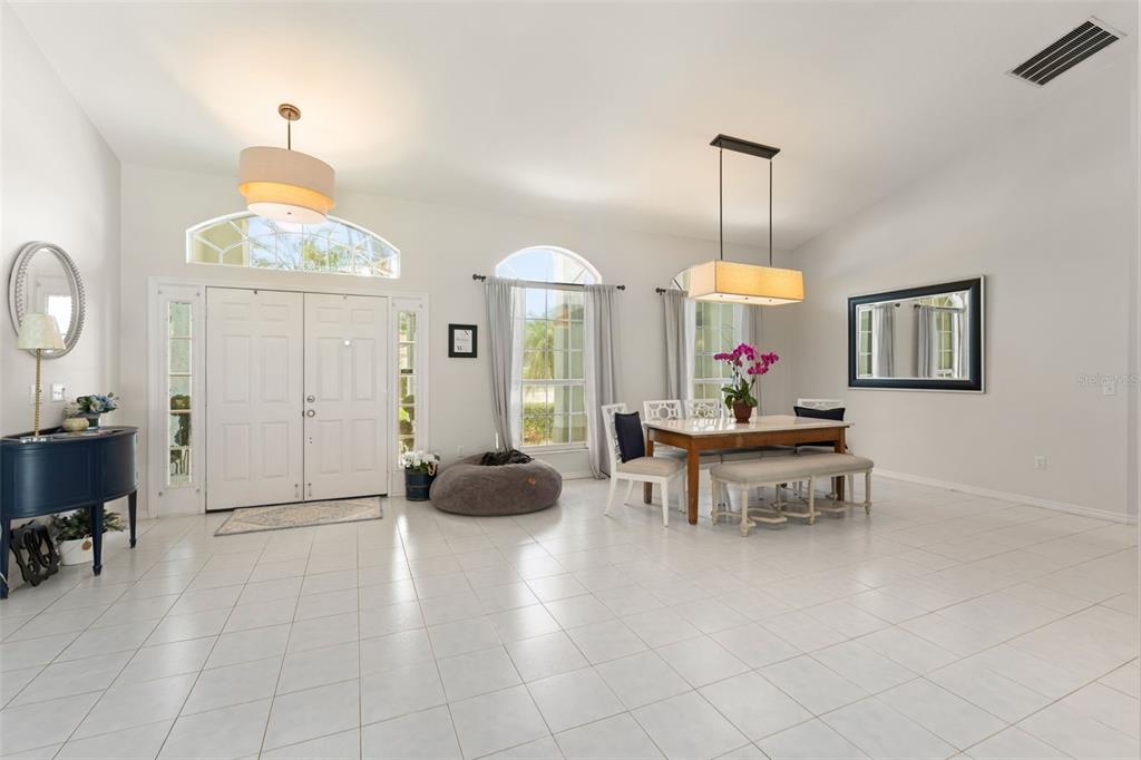 A bright dining area with white tile floors, a rectangular table, and a double-door entrance — 551 WHEATSTONE PLACE, ORLANDO, FL
