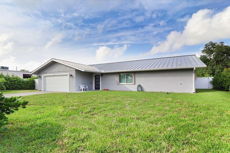 A single-story gray house with a metal roof and an attached garage sits on grass — 615 NE 15th Place, Boynton Beach FL 33435, BOYNTON BEACH, FL