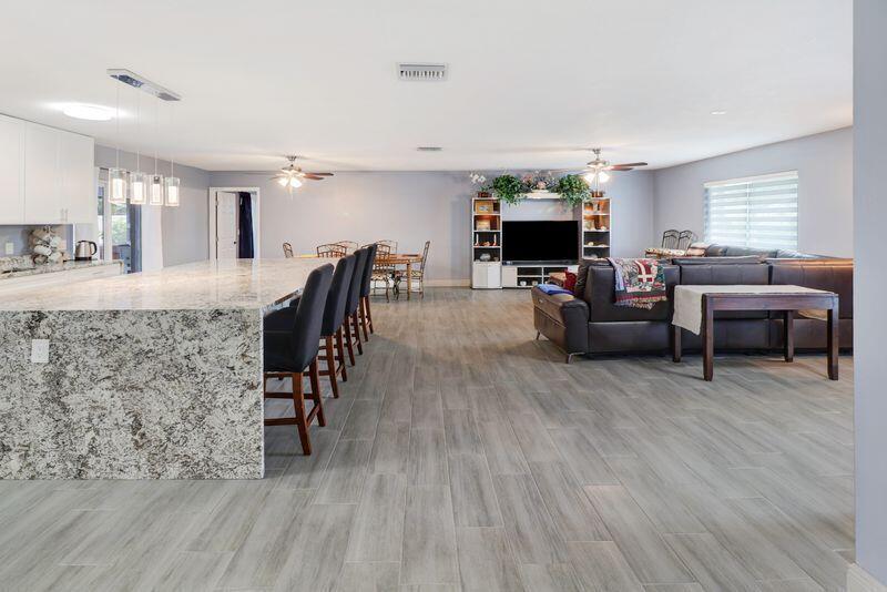 An open-concept living area features a large granite kitchen island, dining table, and sectional sofa — 615 NE 15th Place, Boynton Beach FL 33435, BOYNTON BEACH, FL
