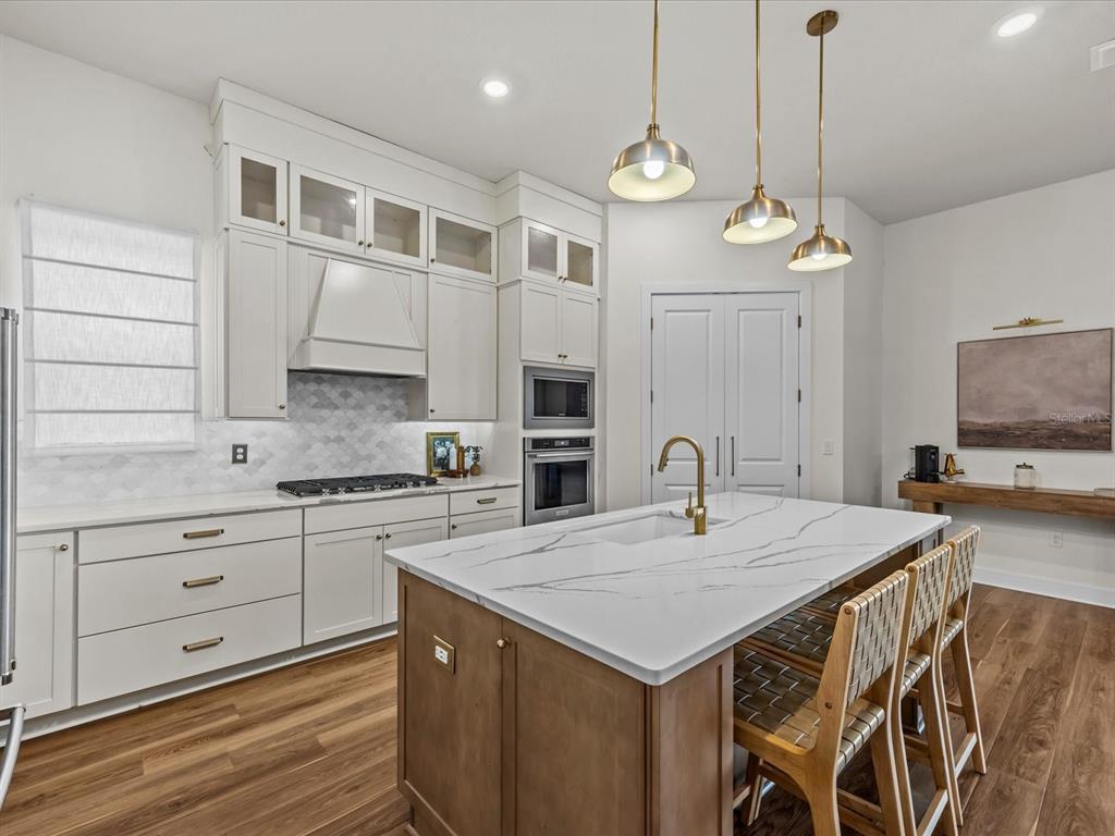 A modern kitchen features white cabinetry, a wood-toned island with a marble countertop, and pendant lighting — 15326 WILLOW RIDGE DRIVE, MONTVERDE, FL
