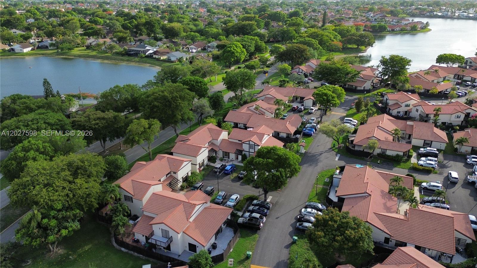 An aerial view shows a residential complex with terracotta-roofed townhomes, parking areas, and lakes — 14950 SW 49th Ln # 7C, Miami FL 33185, MIAMI, FL