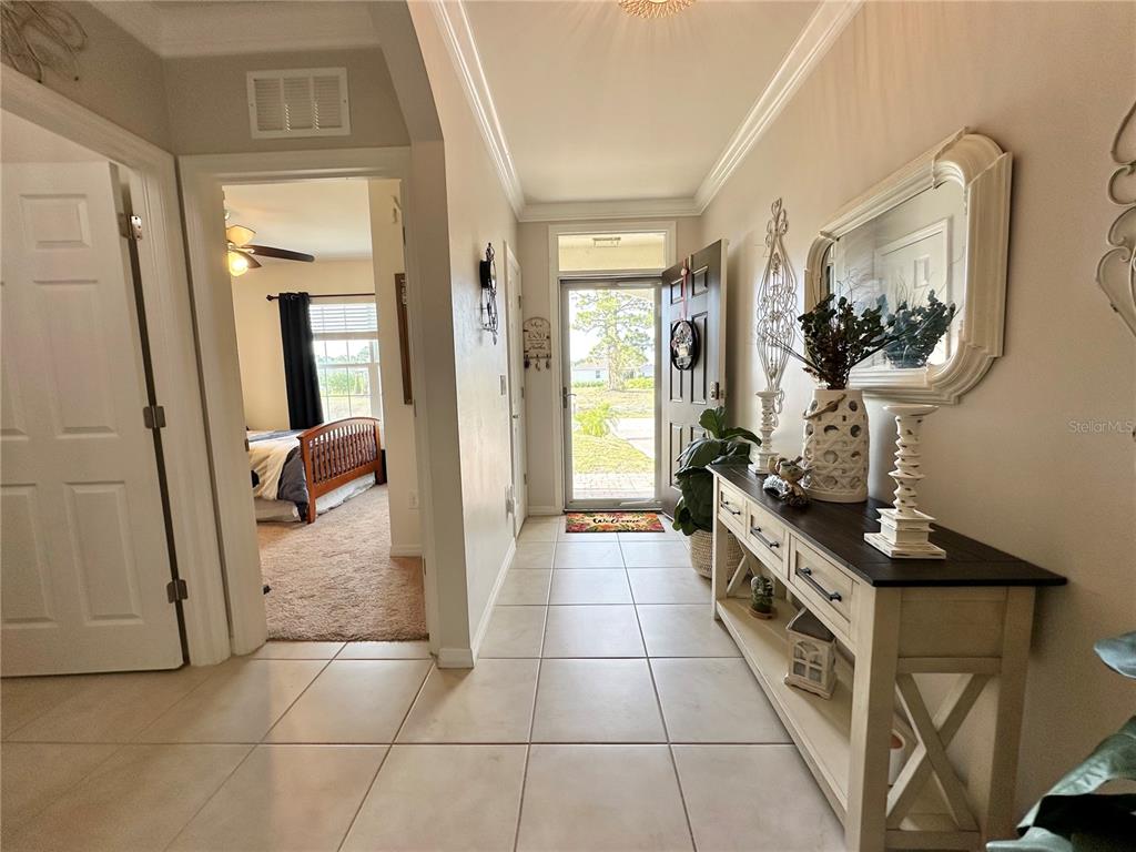 A tiled entryway leads to a front door with a console table and wall mirror — 1708 NW 29TH TERRACE, CAPE CORAL, FL