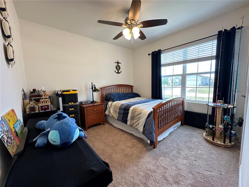 A bedroom features a wooden bed frame, a ceiling fan, and a fishing rod rack — 1708 NW 29TH TERRACE, CAPE CORAL, FL