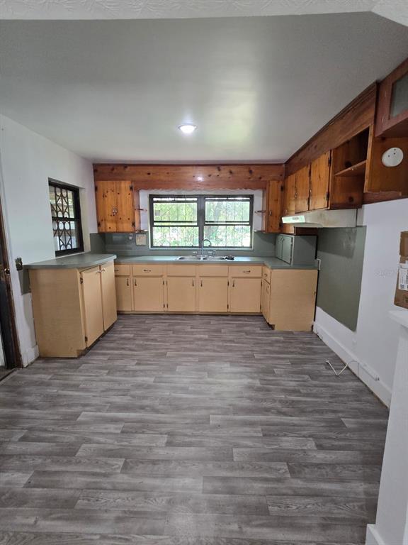 A kitchen features light wood cabinets, a window above the sink, and gray plank flooring — 3328 AVENUE T NW, WINTER HAVEN, FL