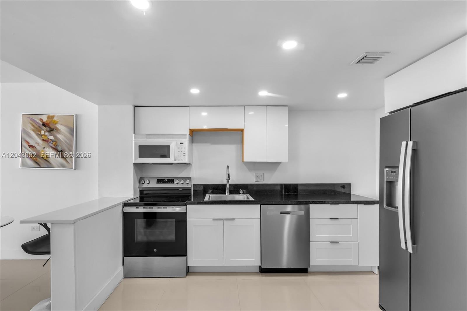 A kitchen features white cabinets, stainless steel appliances, and dark countertops — 801 Brickell Bay Dr # 669, Miami FL 33131, MIAMI, FL
