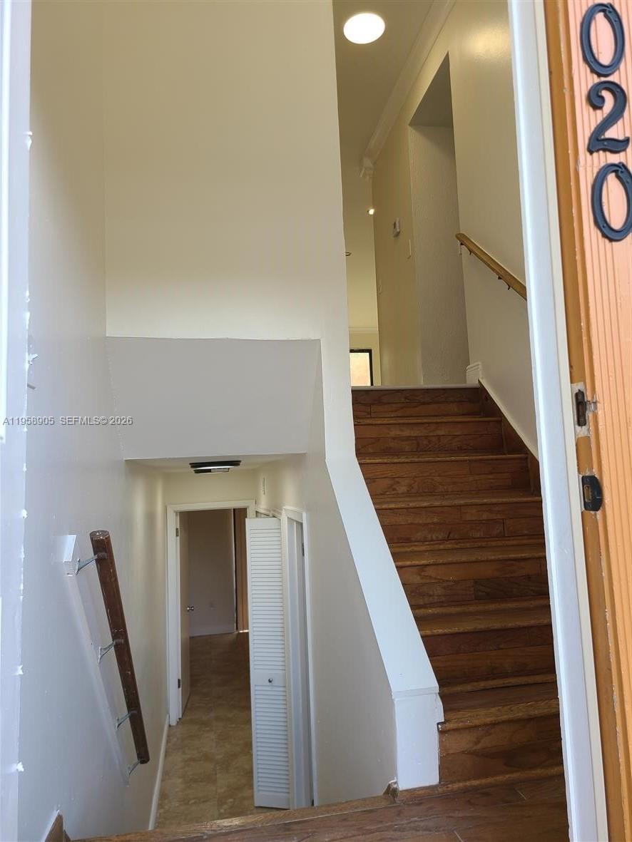 A staircase with wooden treads leads upward from a hallway with white walls — 4020 Del Rio Way, Sunrise FL 33351, SUNRISE, FL
