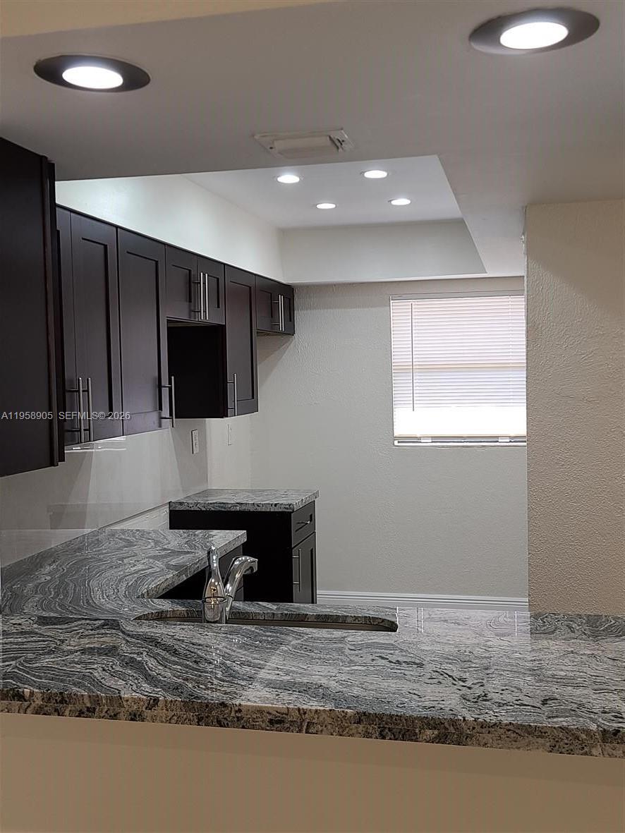 A kitchen features dark wood cabinets, granite countertops, and recessed lighting — 4020 Del Rio Way, Sunrise FL 33351, SUNRISE, FL