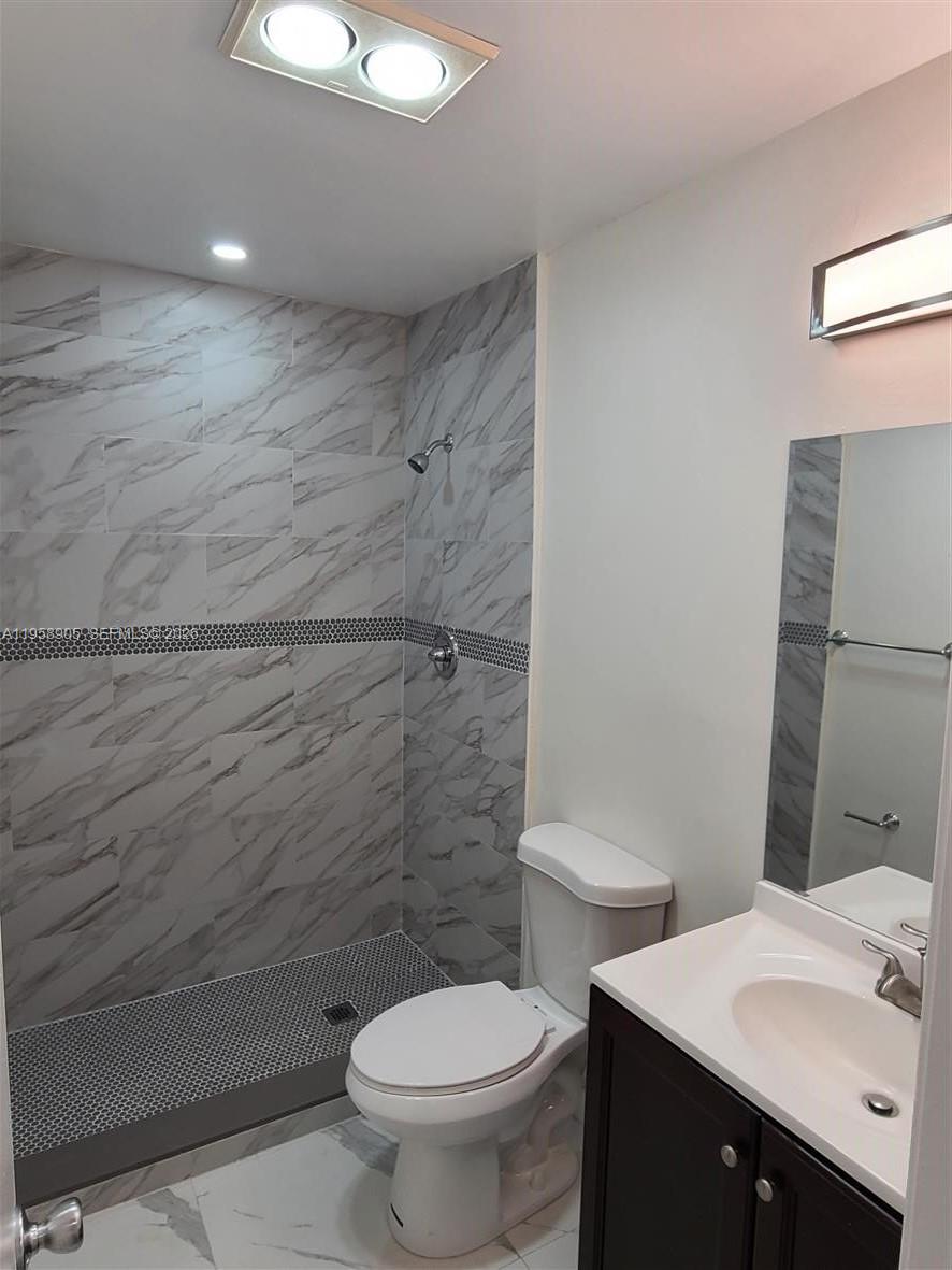A bathroom features a walk-in shower with marble-look tile, a toilet, and a vanity — 4020 Del Rio Way, Sunrise FL 33351, SUNRISE, FL
