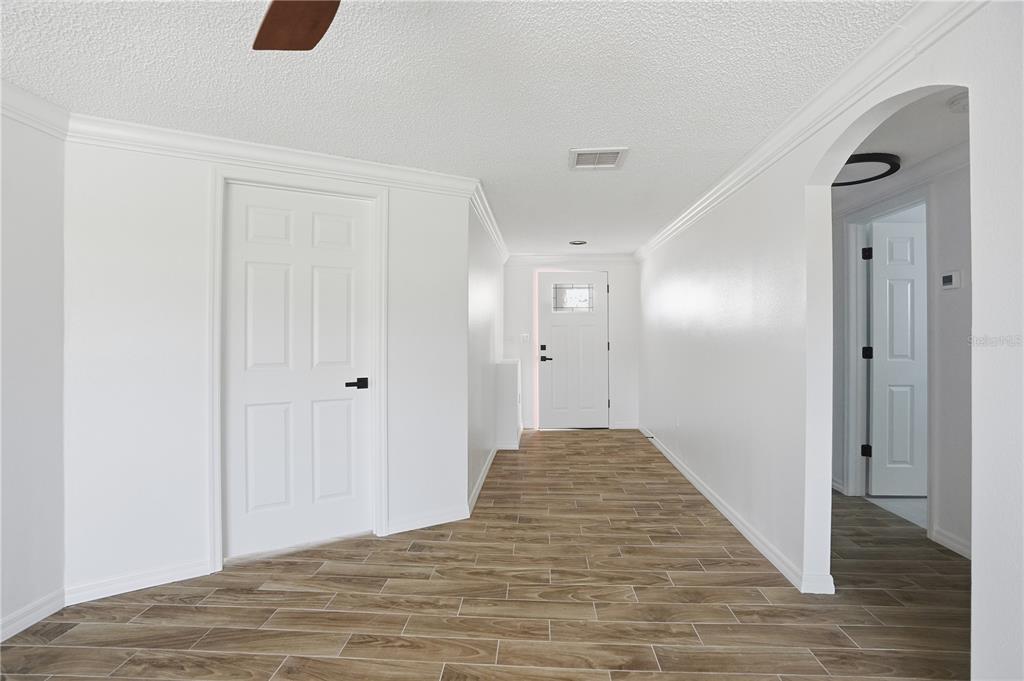 A bright hallway features white walls, crown molding, wood-look tile flooring, and two white doors — 9837 ISLAND HARBOR DRIVE, PORT RICHEY, FL
