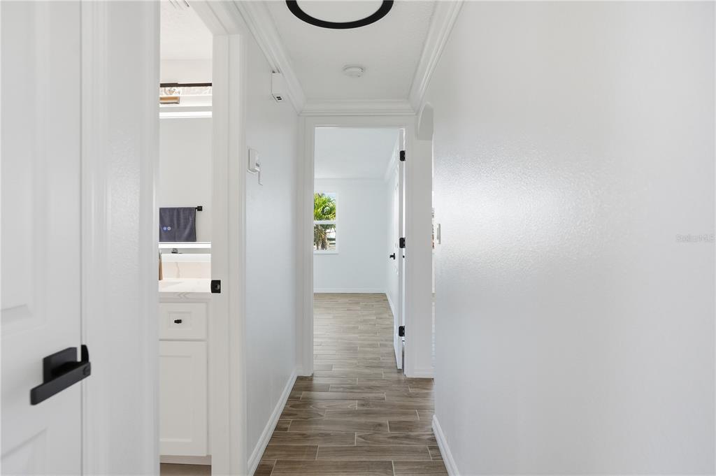 A hallway with wood-look tile flooring leads to a bedroom and a bathroom — 9837 ISLAND HARBOR DRIVE, PORT RICHEY, FL