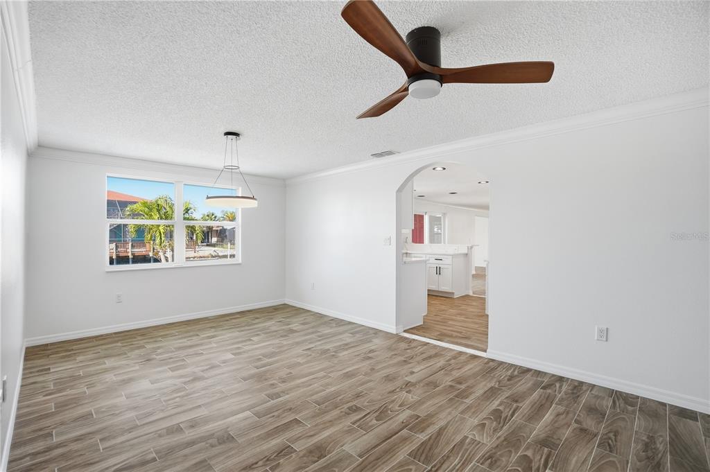 An empty room with wood-look tile flooring, a ceiling fan, and an arched doorway — 9837 ISLAND HARBOR DRIVE, PORT RICHEY, FL