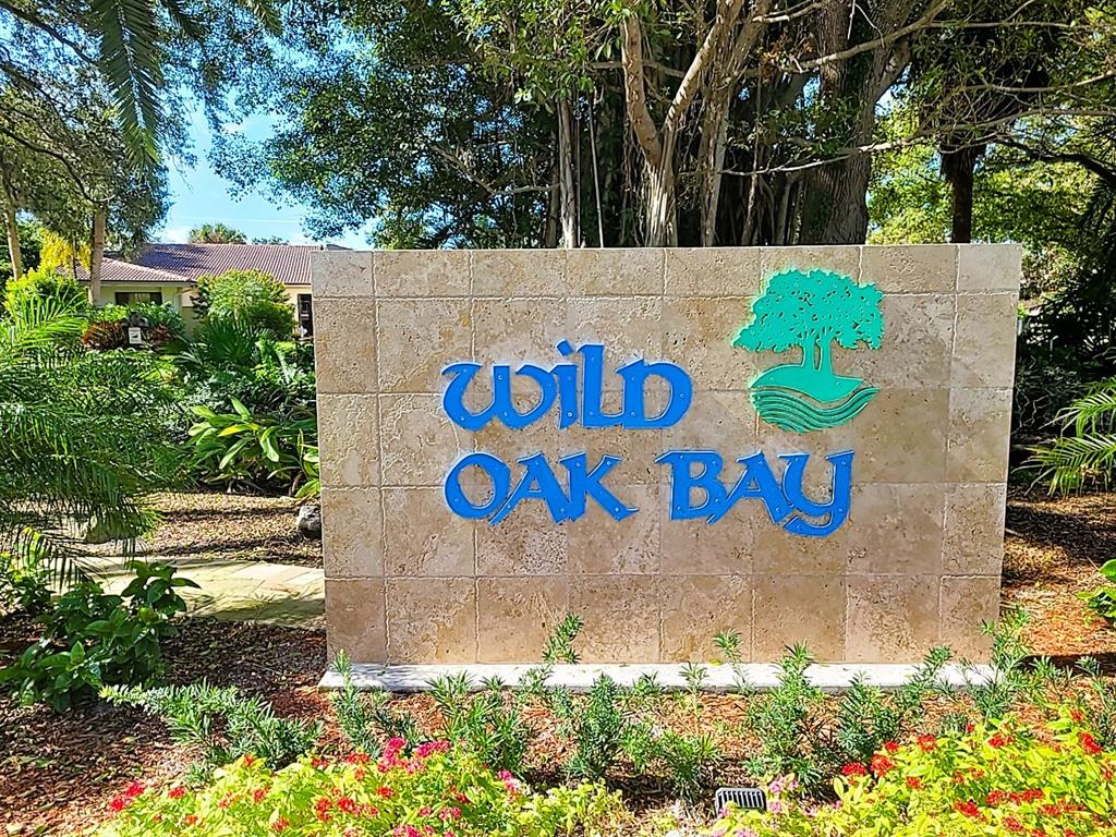 A stone monument sign for Wild Oak Bay stands in a landscaped garden area — 6462 WILD OAK BAY BOULEVARD UNIT 245, BRADENTON, FL