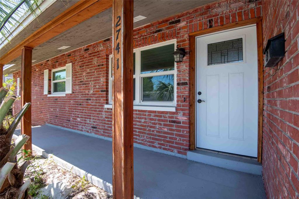 A red brick house exterior features a covered porch, white front door, and wood columns — 2741 37TH STREET S, ST PETERSBURG, FL