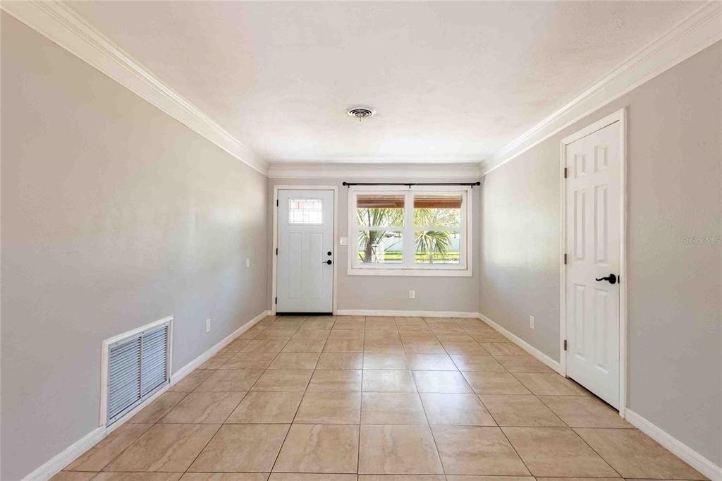 An empty room with light gray walls, tile flooring, a white door, and a window — 2741 37TH STREET S, ST PETERSBURG, FL