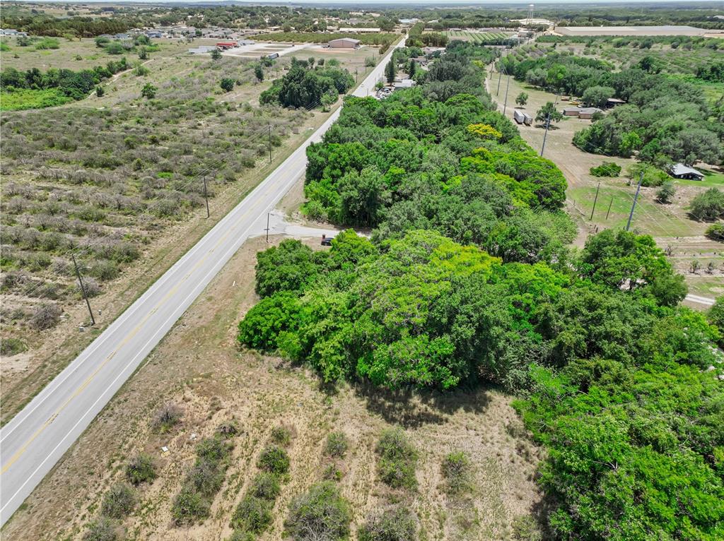 An aerial view shows a paved road running alongside a wooded lot and open fields — SR-17, HAINES CITY, FL
