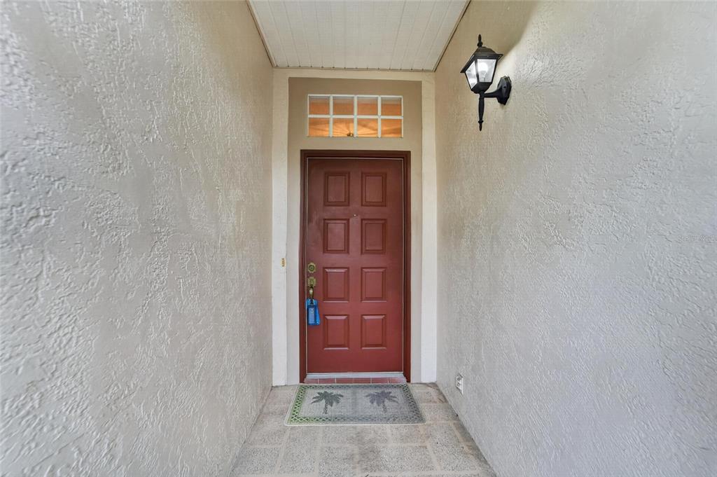 A red front door with a transom window is set within a covered entryway — 1023 MCDANIEL STREET UNIT 139, SUN CITY CENTER, FL